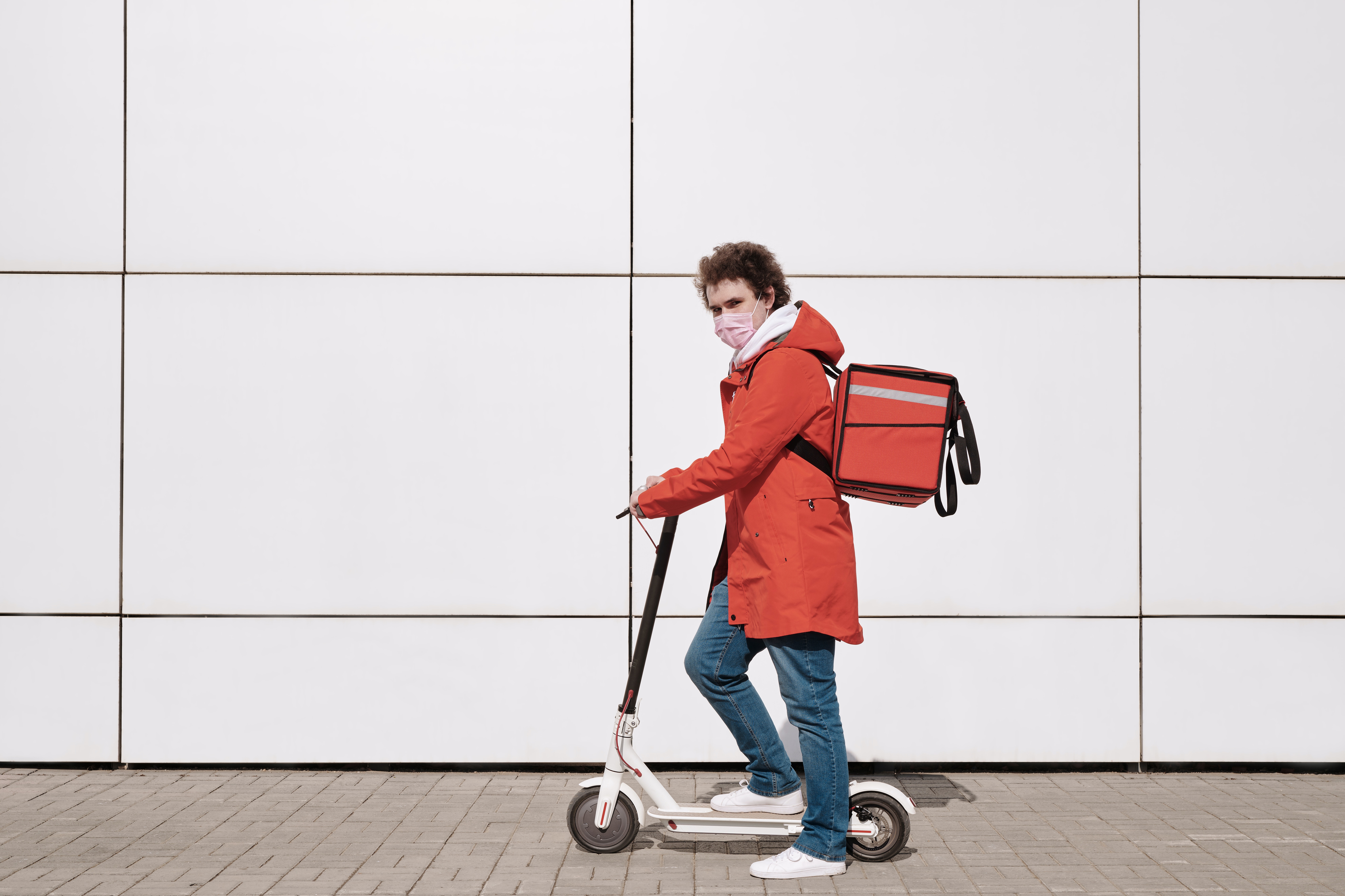 Delivery person on a scooter wearing a mask.