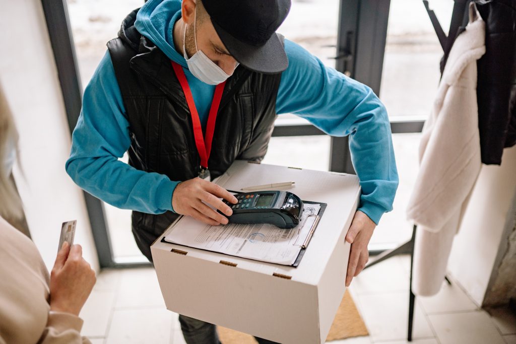 A delivery person delivering in the doorstep an item that was purchased online.